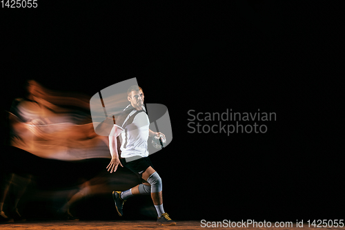 Image of Young handball player against dark studio background in mixed light