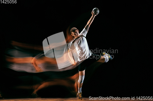 Image of Young handball player against dark studio background in mixed light