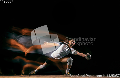 Image of Young handball player against dark studio background in mixed light