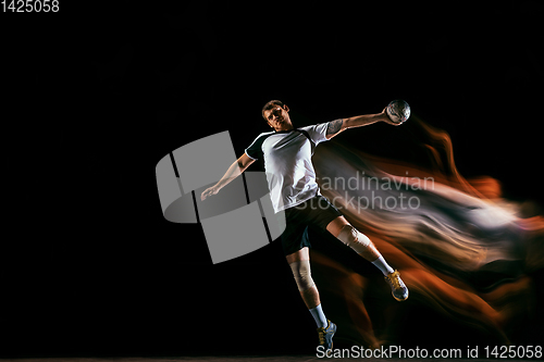 Image of Young handball player against dark studio background in mixed light