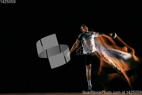 Image of Young handball player against dark studio background in mixed light