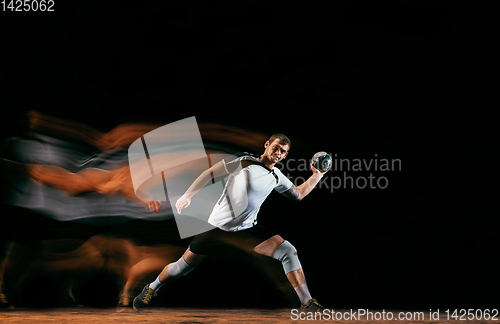 Image of Young handball player against dark studio background in mixed light