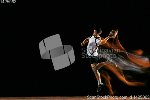 Image of Young handball player against dark studio background in mixed light