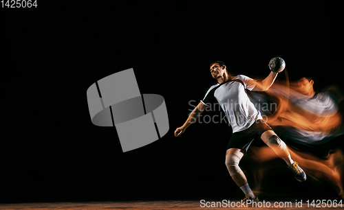 Image of Young handball player against dark studio background in mixed light