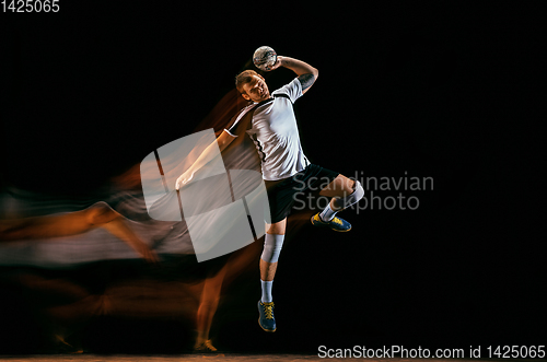 Image of Young handball player against dark studio background in mixed light