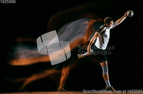 Image of Young handball player against dark studio background in mixed light