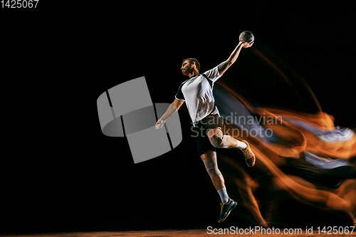 Image of Young handball player against dark studio background in mixed light