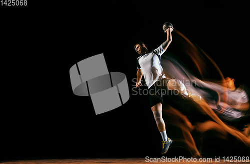 Image of Young handball player against dark studio background in mixed light