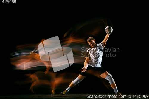 Image of Young handball player against dark studio background in mixed light