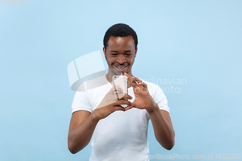 Image of Half-length close up portrait of young man on blue background.