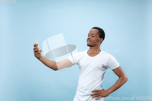 Image of Half-length close up portrait of young man on blue background.