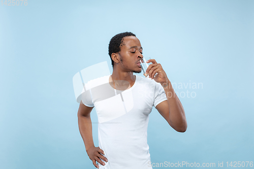 Image of Half-length close up portrait of young man on blue background.