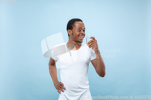Image of Half-length close up portrait of young man on blue background.