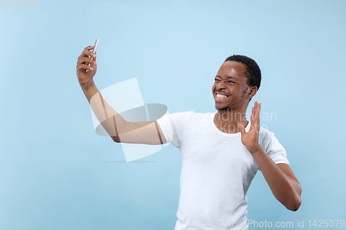 Image of Half-length close up portrait of young man on blue background.