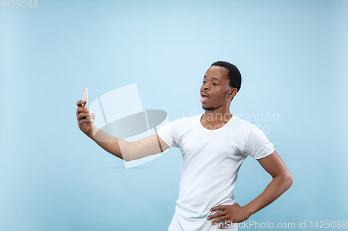 Image of Half-length close up portrait of young man on blue background.