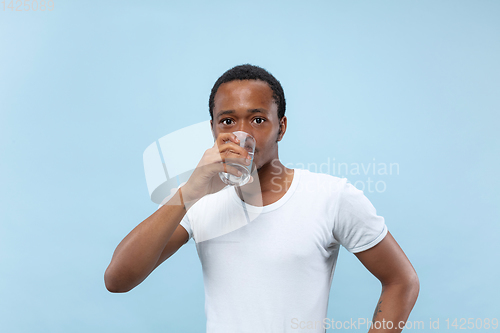 Image of Half-length close up portrait of young man on blue background.