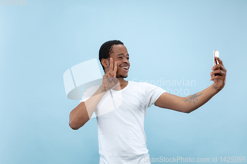 Image of Half-length close up portrait of young man on blue background.