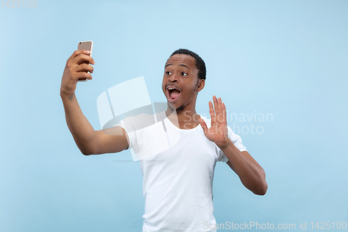 Image of Half-length close up portrait of young man on blue background.