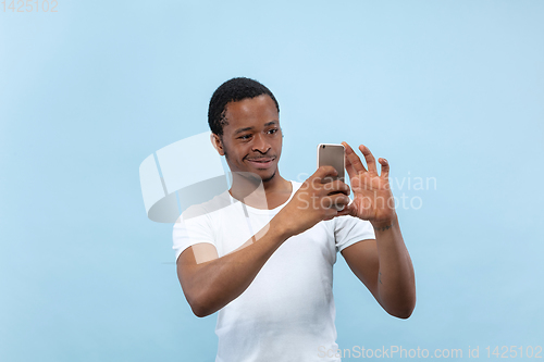 Image of Half-length close up portrait of young man on blue background.