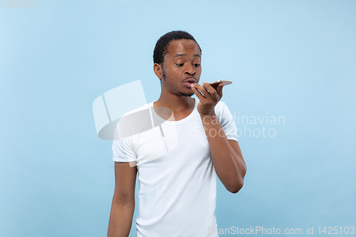 Image of Half-length close up portrait of young man on blue background.