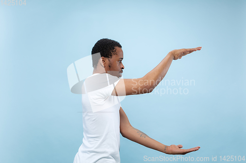 Image of Half-length close up portrait of young man on blue background.