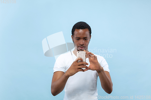 Image of Half-length close up portrait of young man on blue background.