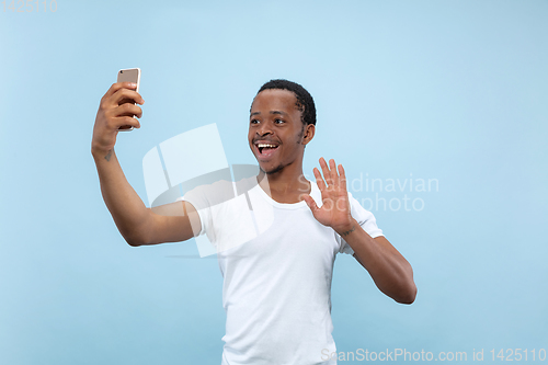 Image of Half-length close up portrait of young man on blue background.