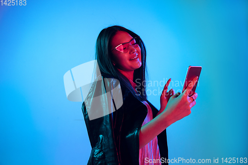 Image of Beautiful girl\'s facial expression in neon light on blue studio background