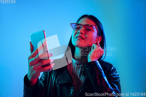 Image of Beautiful girl\'s facial expression in neon light on blue studio background