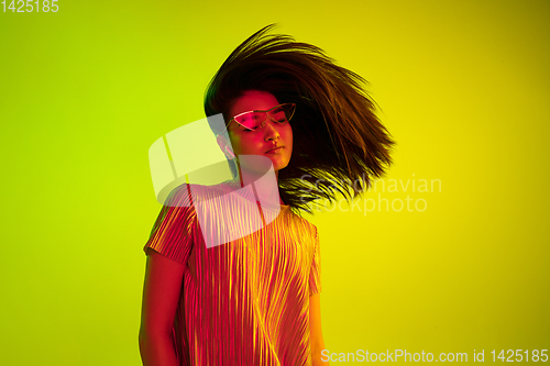 Image of Beautiful girl\'s facial expression in neon light on yellow studio background