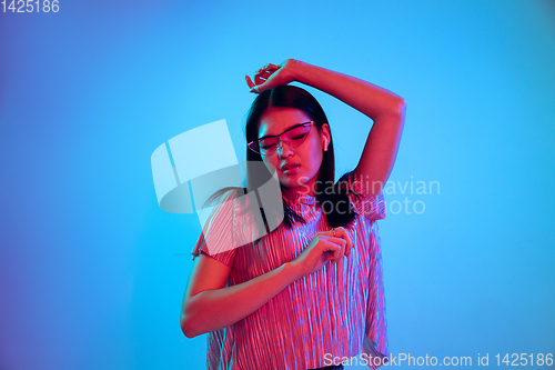 Image of Beautiful girl\'s facial expression in neon light on blue studio background