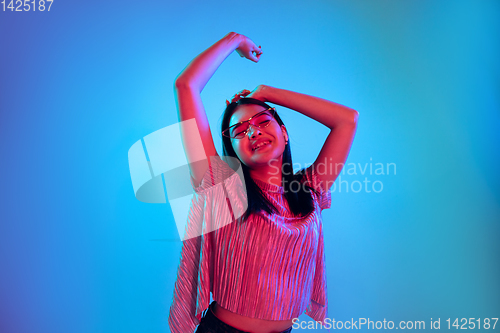Image of Beautiful girl\'s facial expression in neon light on blue studio background