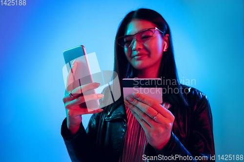 Image of Beautiful girl\'s facial expression in neon light on blue studio background