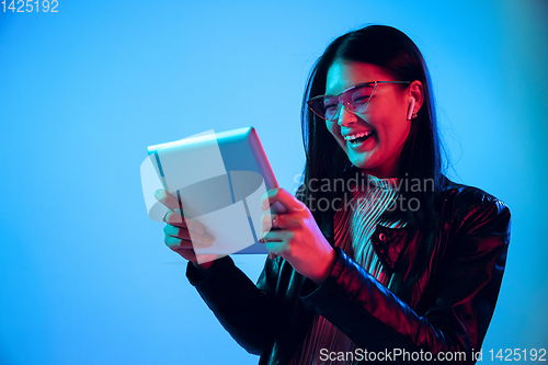 Image of Beautiful girl\'s facial expression in neon light on blue studio background