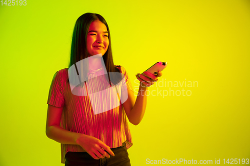 Image of Beautiful girl\'s facial expression in neon light on yellow studio background