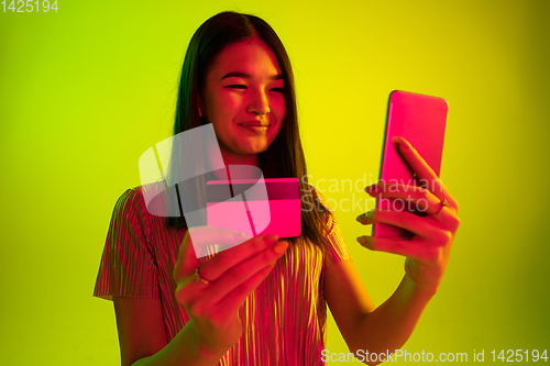 Image of Beautiful girl\'s facial expression in neon light on yellow studio background