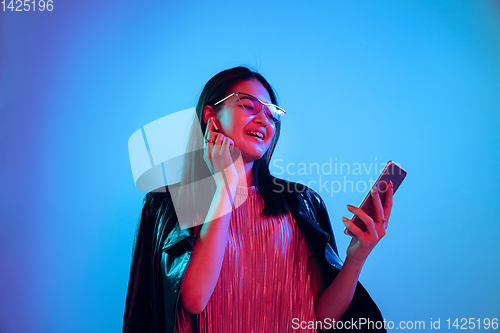 Image of Beautiful girl\'s facial expression in neon light on blue studio background