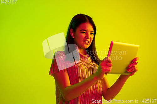 Image of Beautiful girl\'s facial expression in neon light on yellow studio background