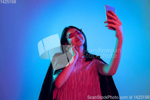 Image of Beautiful girl\'s facial expression in neon light on blue studio background