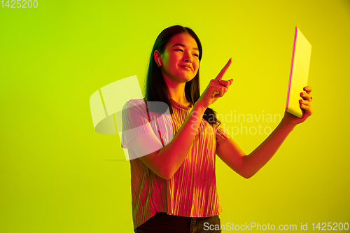 Image of Beautiful girl\'s facial expression in neon light on yellow studio background
