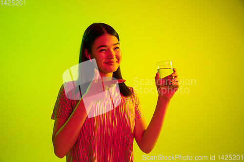 Image of Beautiful girl\'s facial expression in neon light on yellow studio background