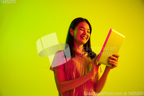 Image of Beautiful girl\'s facial expression in neon light on yellow studio background