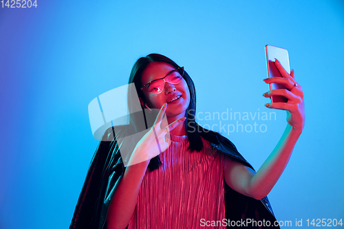 Image of Beautiful girl\'s facial expression in neon light on blue studio background