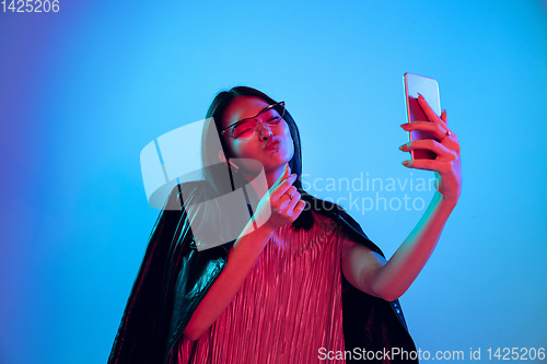 Image of Beautiful girl\'s facial expression in neon light on blue studio background