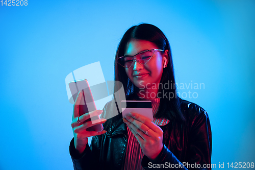 Image of Beautiful girl\'s facial expression in neon light on blue studio background