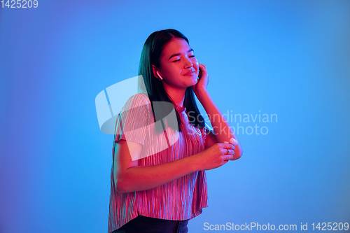 Image of Beautiful girl\'s facial expression in neon light on blue studio background