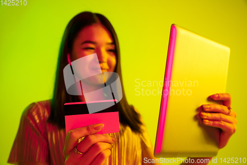 Image of Beautiful girl\'s facial expression in neon light on yellow studio background