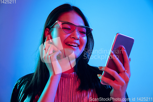 Image of Beautiful girl\'s facial expression in neon light on blue studio background