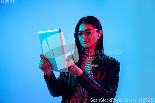 Image of Beautiful girl\'s facial expression in neon light on blue studio background