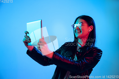 Image of Beautiful girl\'s facial expression in neon light on blue studio background